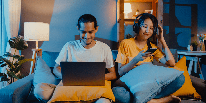 Freelance asia couple man and woman in casual hasband work laptop computer at night enjoy happy relax with wife wear headphone listen music in smartphone sing dance on couch at house, Married life.